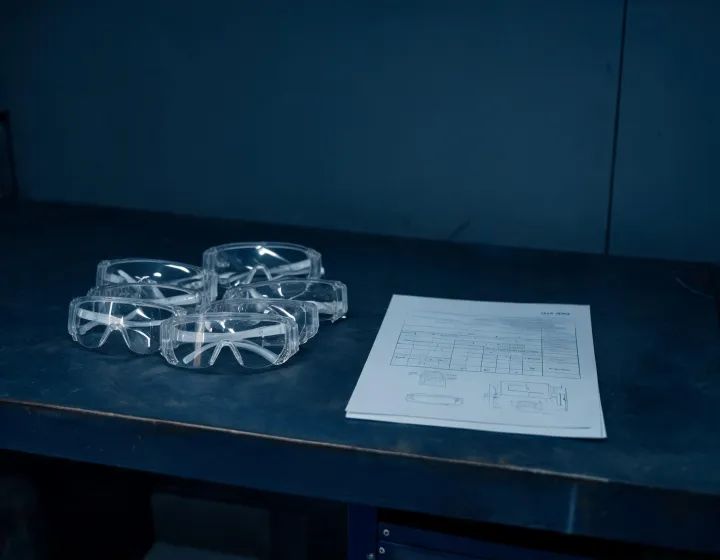Unlabeled custom safety glasses beside a written procurement brief